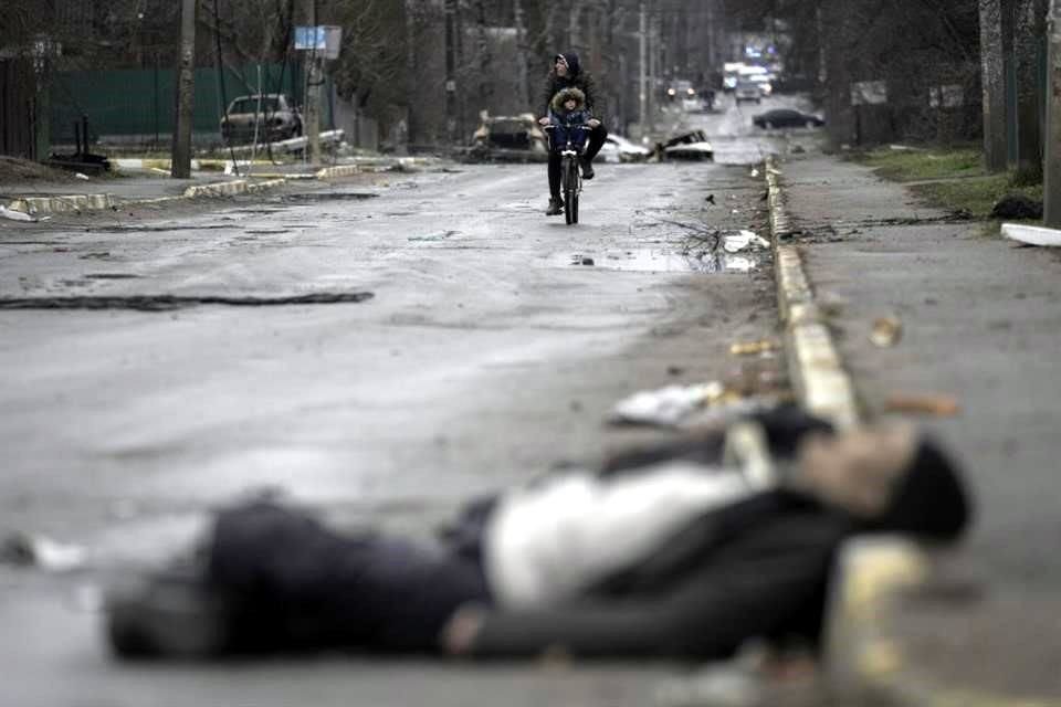 Un hombre y un niño recorren las calles de Bucha, en la región de Kiev, después de que las fuerzas rusas se retiraran, en medio de cadáveres.