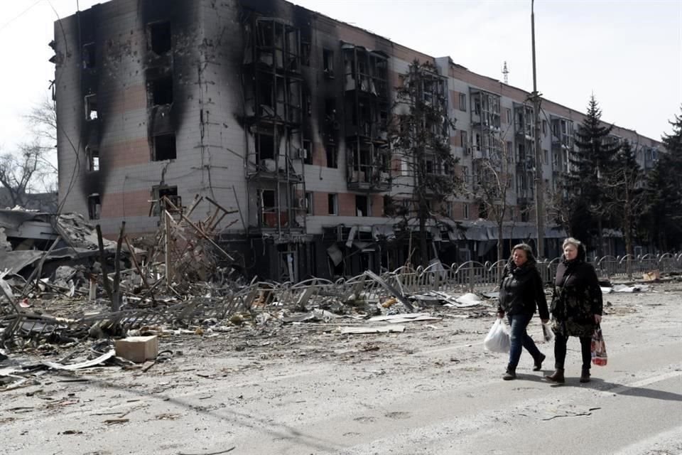 Personas caminan por edificios destruidos en Mariúpol.