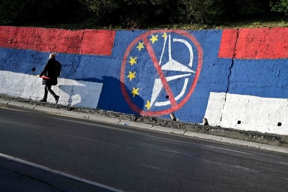 Una persona camina junto a un mural contra la OTAN en Belgrado.