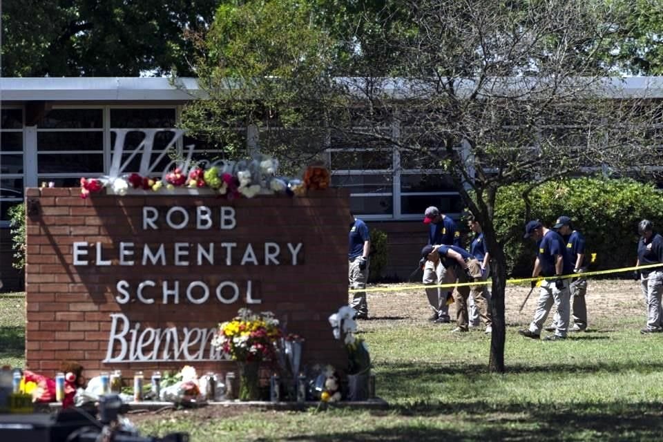 Agentes investigan el tiroteo en la escuela primaria junto a un memorial con flores en la Escuela Robb.