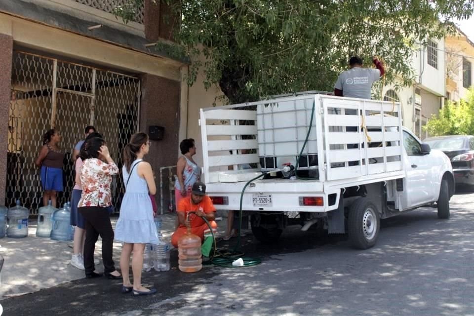 Vecinos del sur de Monterrey rellenan garrafones con agua para sus viviendas.