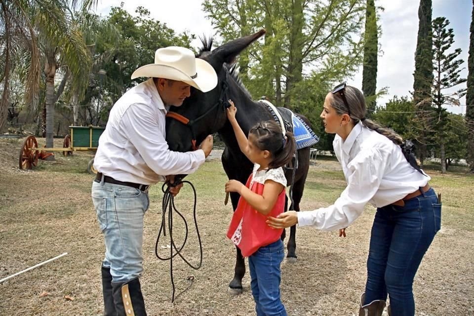 El especialista en educación Azael Cortés Dueñas y la psicóloga Virginia Flores acercan a una pequeña con un burro.