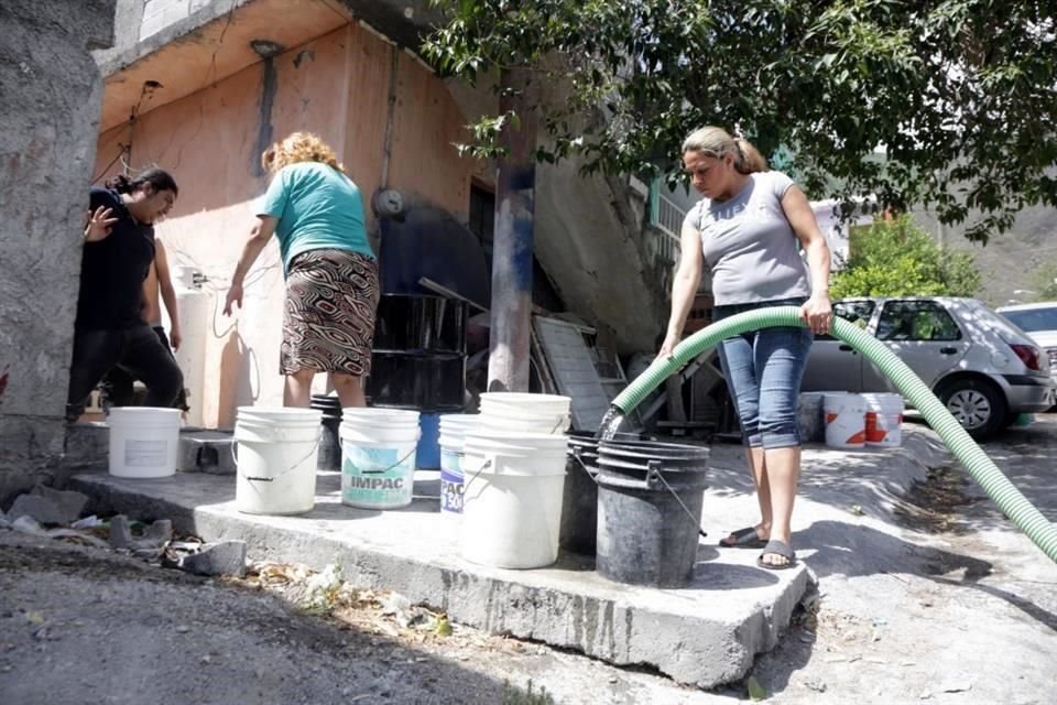 DANDO LA MANO. Una vecina acompañó al operador de una pipa y llenó cada cubeta y garrafón, en Laderas del Mirador.