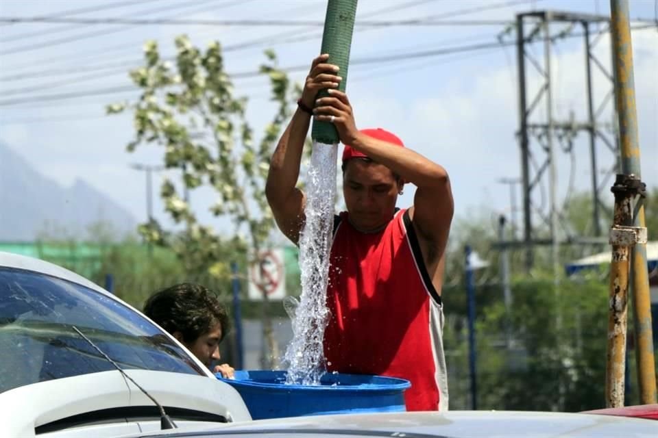 Joel sube un tambo de 200 litros a la parte alta de Lomas de Aztlán, en Escobedo, para que sus vecinos tengan agua.