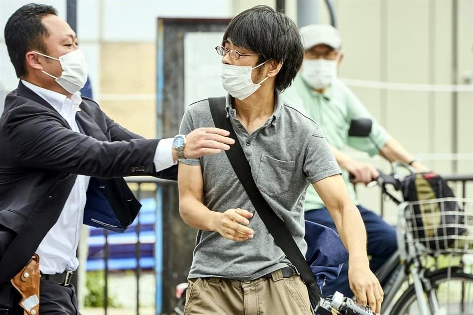 Tetsuya Yamagami (derecha) con un arma, es detenido en Nara, Japón.