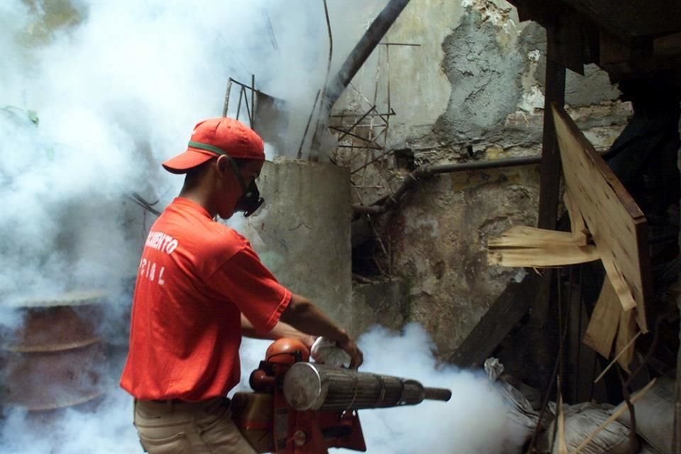 Un trabajador fumiga un edificio en La Habana para matar mosquitos que general el dengue.