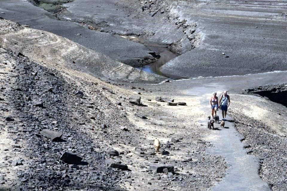 Dos personas cruzan lo que fue un antiguo puente de carga expuesto por los bajos niveles de agua en el embalse de Baitings en Yorkshire.