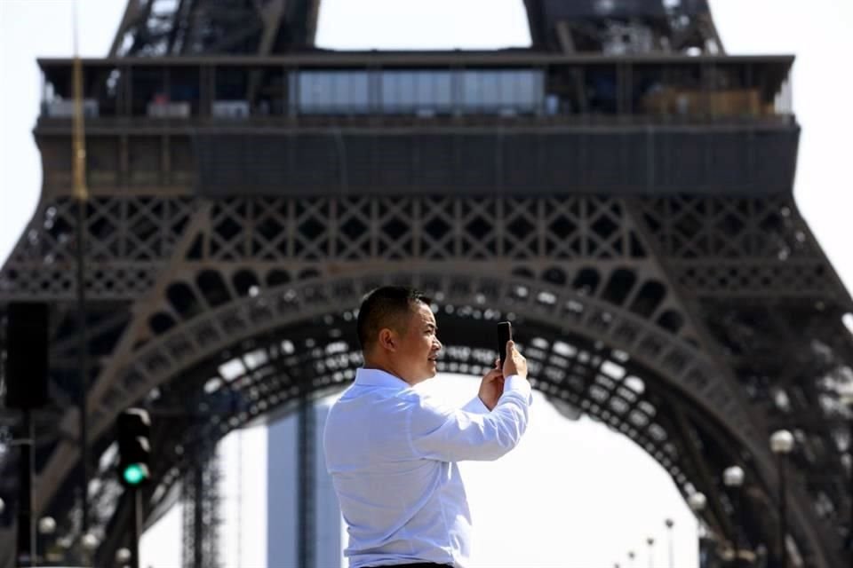 Un turista toma una foto debajo de la Torre Eiffel, en parís, Francia.