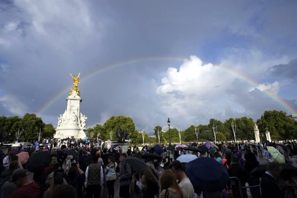 Un arcoíris se ve en el cielo mientras multitudes se reúnen en el Palacio de Buckingham.