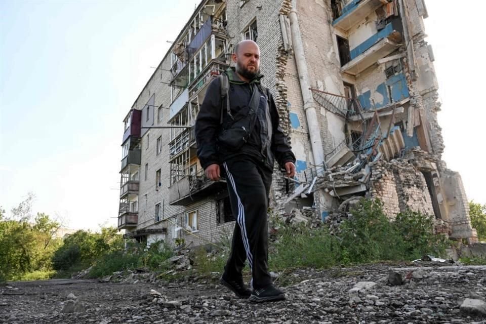 Un residente de Izium camina cerca de un edificio dañado por bombardeos rusos.