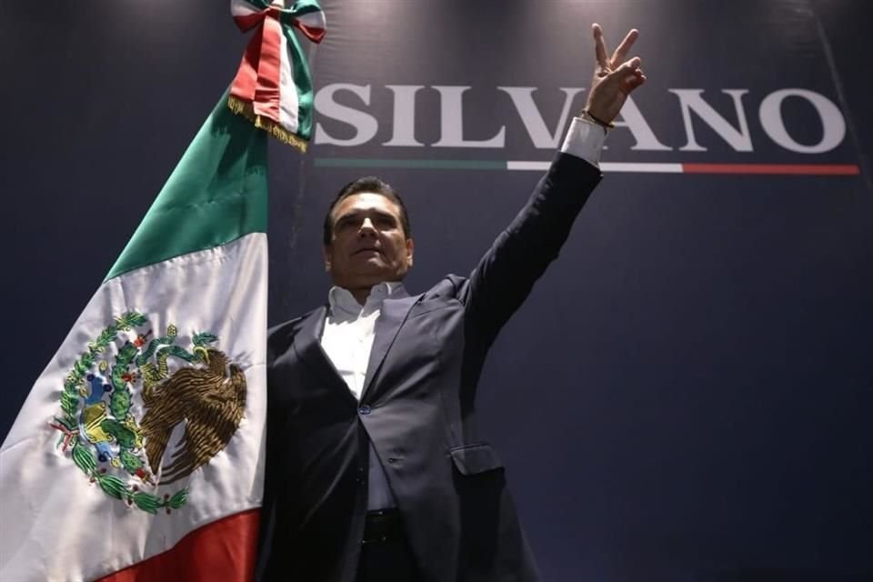 Silvano Aureoles alza su mano con la 'v' de la victoria en un hotel de la Ciudad de México.