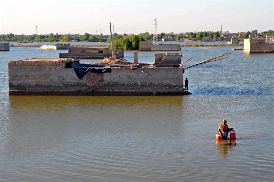 Una mujer avanza entre las inundaciones para llenar recipientes con agua potable, en Jaffarabad, Pakistán.