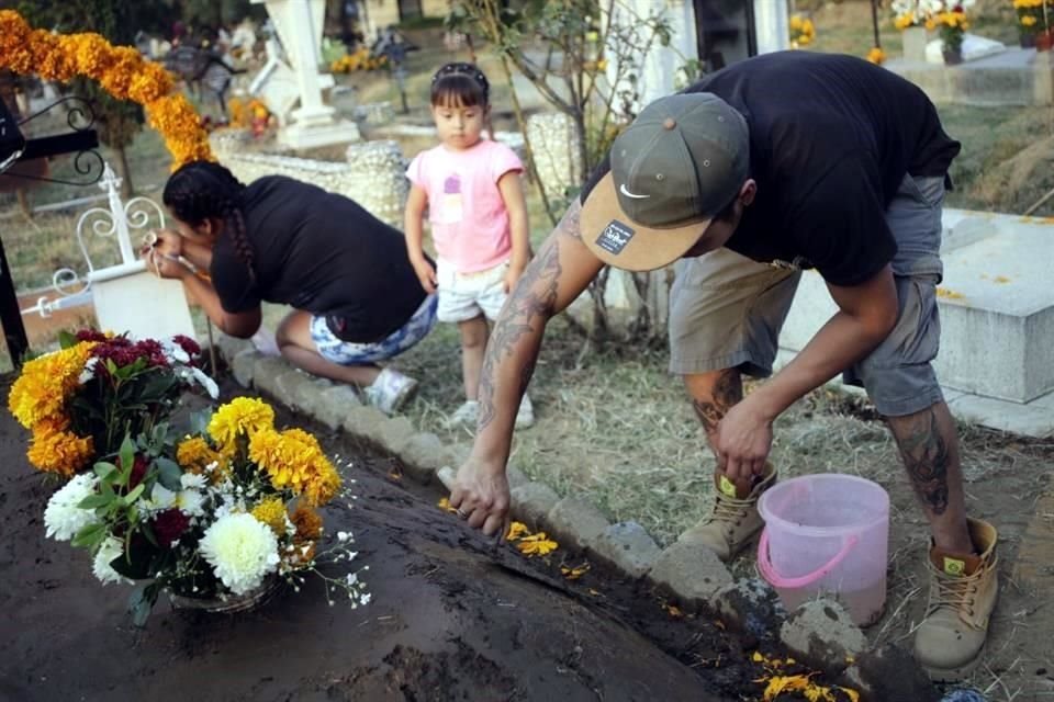 Con diseños alusivos a calaveras, xoloitzcuintles y cruces, habitantes de San Antonio Tecomitl, en Milpa Alta adornan tumbas para recordar a sus difuntos.