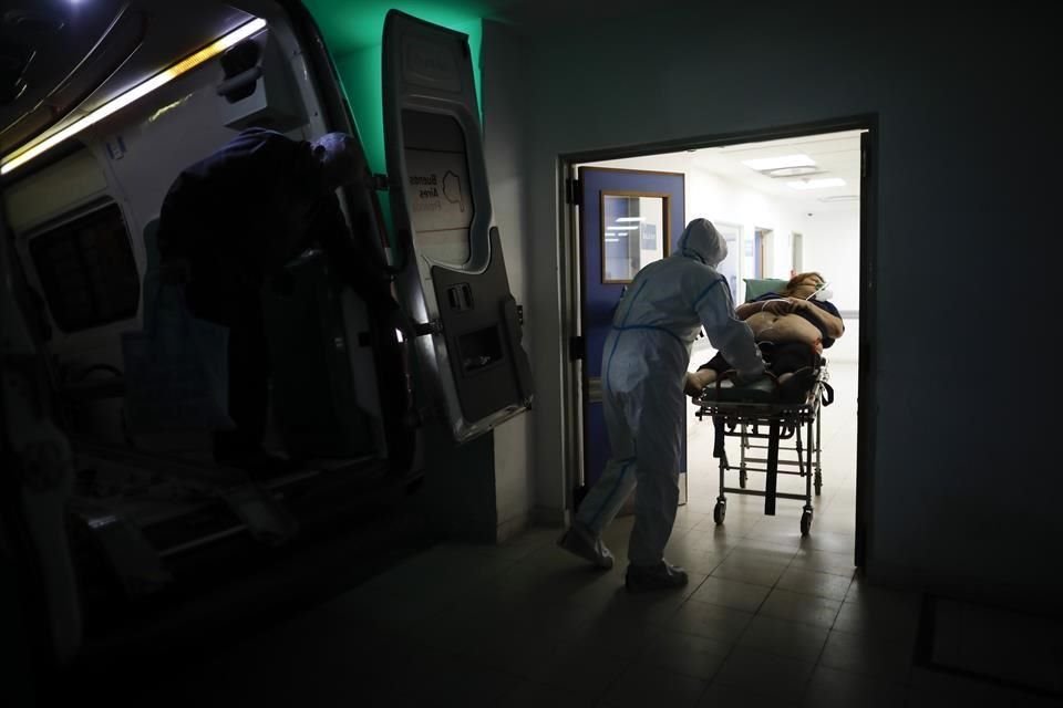 Un trabajador de la salud ingresa a una persona sospechosa de padecer Covid a un hospital en Argentina.