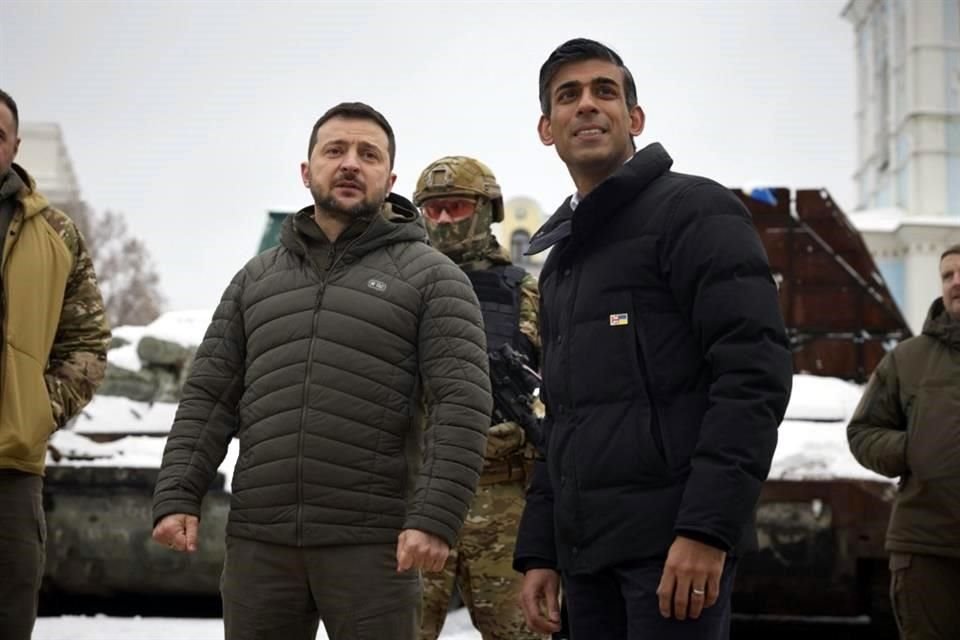 El Presidente ucraniano, Volodymyr Zelensk (izq.), acompaña al Primer Ministro británico, Rishi Sunak, durante un recorrido por una fila de vehículos militares rusos destruidos en el centro de Kiev.