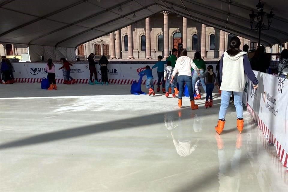 Algunos de los asistentes alertan a sus familiares sobre no patinar sobre el área que se deshiela.