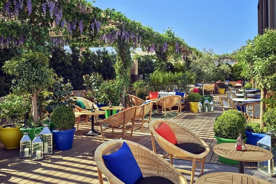 En el exterior, la terraza de Oroya es un seductor espacio verde con una chimenea y una pérgola cubierta de vides.