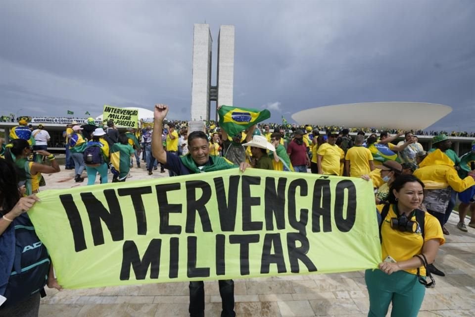 Simpatizantes de Jair Bolsonaro sostienen una pancarta que dice en portugués 'Intervención militar' mientras asaltan el edificio del Congreso Nacional en Brasilia, Brasil.