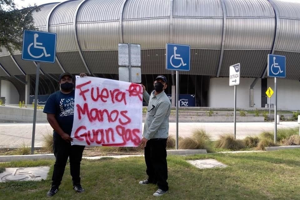 Dos presuntos integrantes de La Adicción portan una de las mantas afuera del Estadio BBVA.