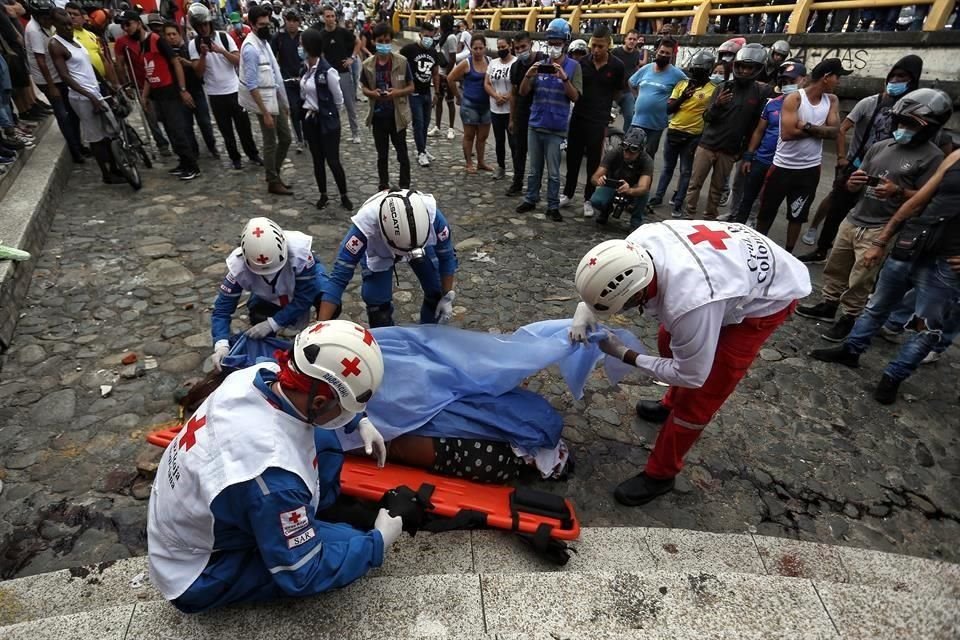 Paramédicos recogen el cuerpo de un funcionario que fue linchado por un grupo de personas que lo acusaron de matar a dos manifestantes que bloqueaban su camino, en Cali.