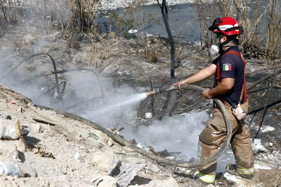 Bomberos, personal de Protección Civil y de la Secretaria de Medio Ambiente realizan diversos trabajos para sofocar un incendio en el Río Pesquería.