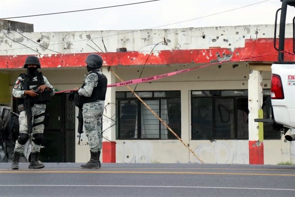 Elementos de la Guardia Nacional vigilan la zona donde calcinaron a cuatro personas tras un ataque a balazos entre bandas rivales.