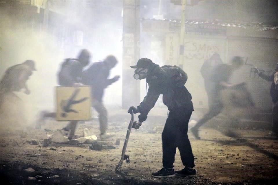 Manifestantes corren ante la llegada de policías en las calles de Bogotá.