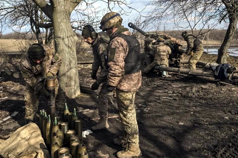 Militares ucranianos preparan municiones para disparar con un obús de 105 mm hacia posiciones rusas.