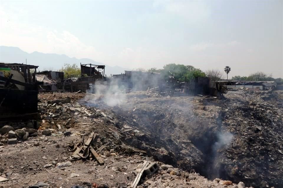 El área incendiada de un tiradero fue cubierta con basura, y ahora salen llamas y humo de ese punto.