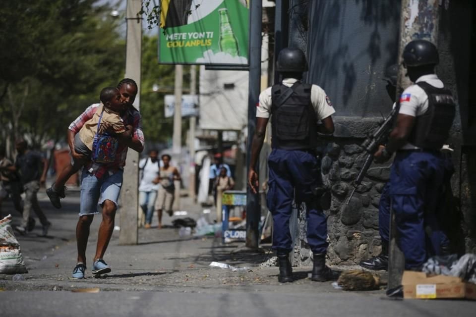 Un padre carga a su hijo luego de pasar por él a la escuela en medio de un operativo policial contra pandillas, el 3 de marzo de 2023, en Puerto Príncipe, Haití.