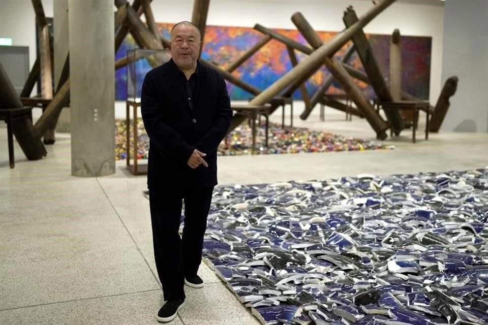 El artista Ai Weiwei posa junto a los miles de fragmentos de sus esculturas de porcelana que fueron destruidas en su estudio de Pekín, ahora expuestas en el Museo del Diseño de Londres.