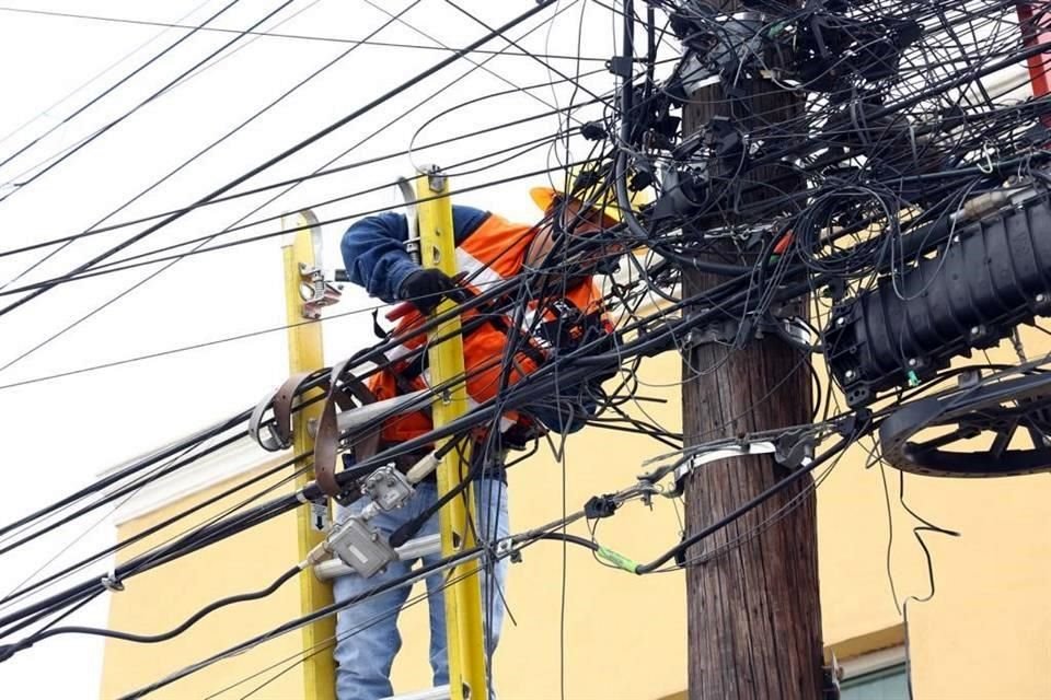 Un trabajador realiza maniobras para retirar los cables en desuso dentro de la 'telaraña', en la Colonia Villas de Universidad.
