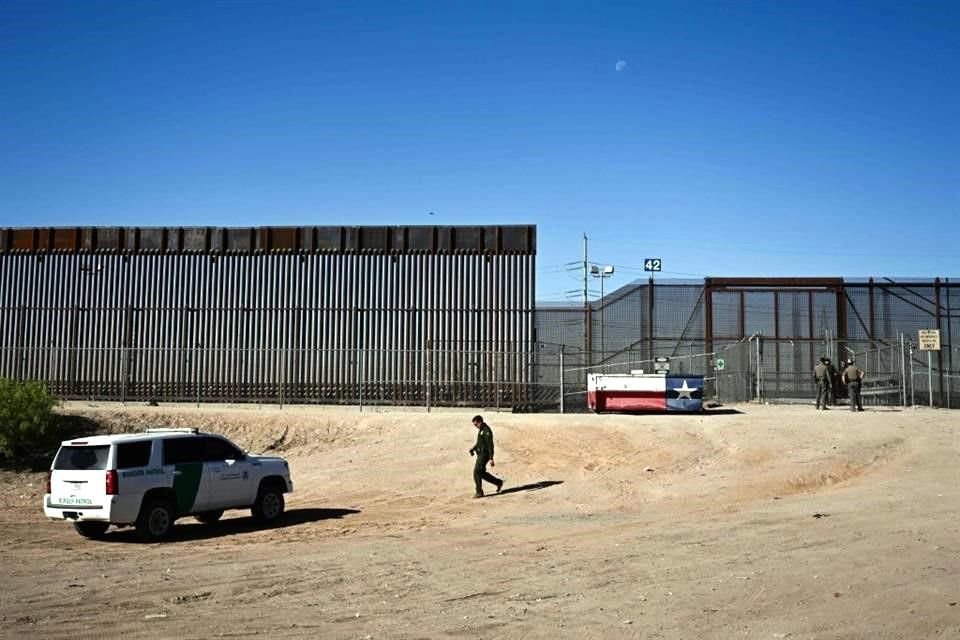 Un agente de la Patrulla Fronteriza de Aduanas y Protección Fronteriza camina hacia un vehículo a lo largo del muro fronterizo con México.