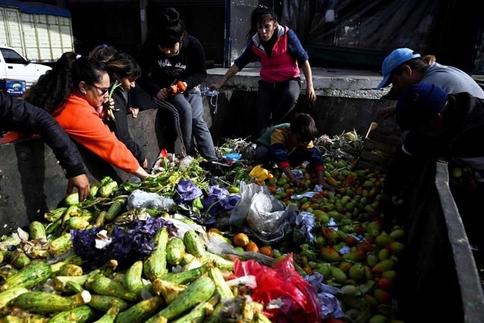 La gente busca comida dentro de un bote de basura donde se depositan las frutas y verduras desechadas en el Mercado Central de Buenos Aires.