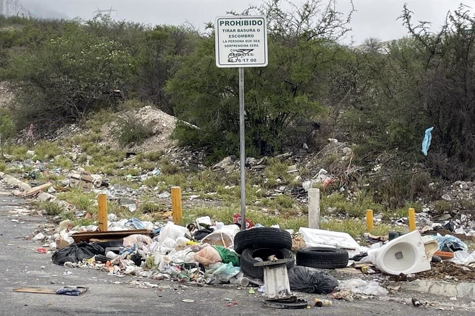 Desechos como llantas y plásticos rodean la advertencia que prohíbe tirar basura en el lugar, en la Colonia Mirador de la Huasteca.