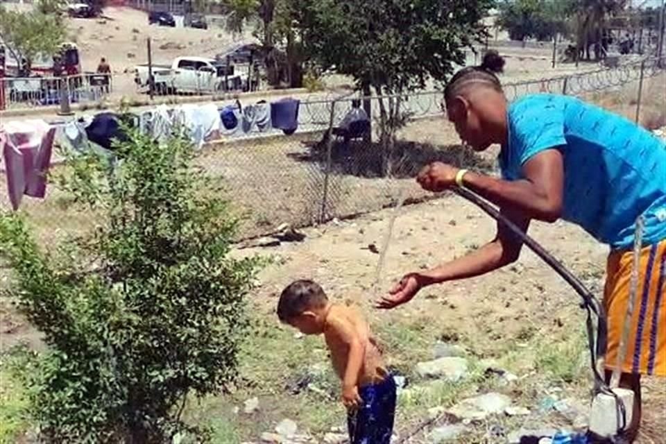 La manguera en el campamento del INM es utilizada por varios migrantes para refrescarse ante el intenso calor que se registra en Juárez, Chihuahua.