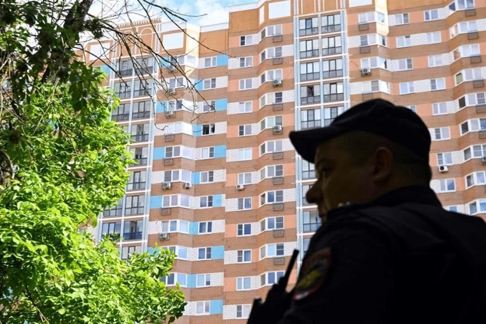 Un oficial de policía hace guardia afuera de un edificio de apartamentos de varios pisos después de un ataque con drones.