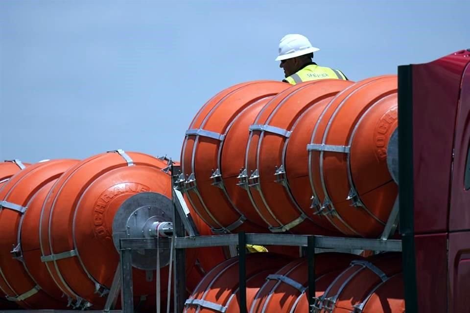 Un trabajador ayuda a descargar grandes boyas que se desplegarán en el Río Bravo.