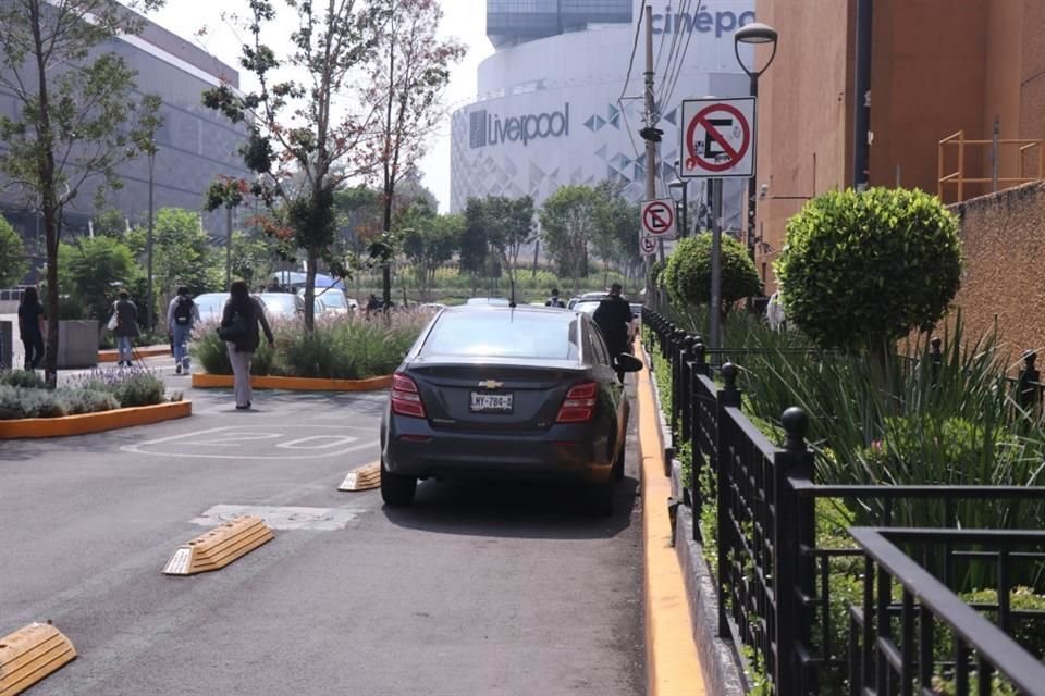 El carril confinado está invadido por automóviles que usan el espacio que quedó libre como una extensión del estacionamiento de la plaza.