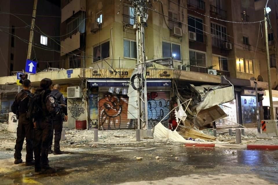 Miembros de las fuerzas de seguridad israelíes se encuentran a lo largo de una calle llena de escombros en Tel Aviv.