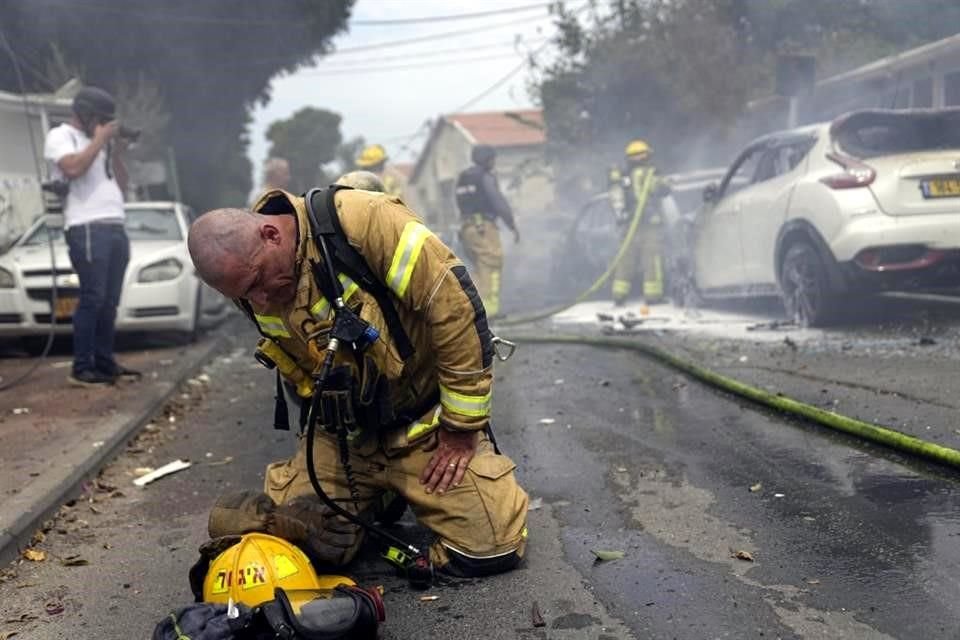 Un bombero israelí se arrodilla exhausto después de que él y sus compañeros apagaron vehículos incendiados por los cohetes lanzados desde la Franja de Gaza.