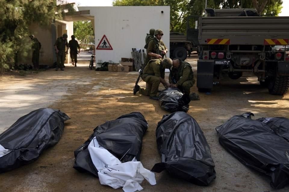 Soldados israelíes junto a los cuerpos de israelíes asesinados por combatientes de Hamas.