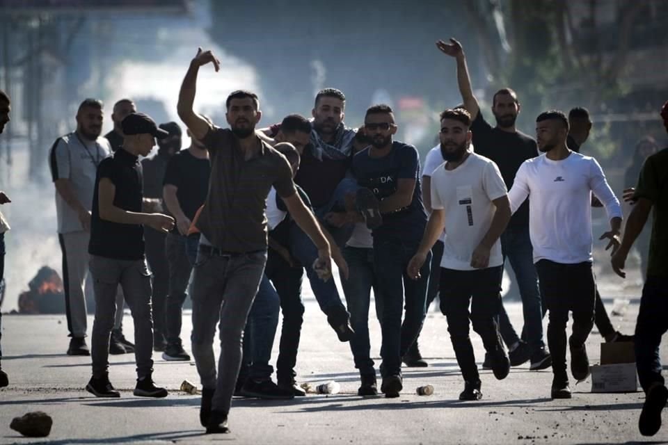 Manifestantes palestinos cargan heridos durante enfrentamientos con fuerzas israelíes luego de una manifestación en apoyo de la Franja de Gaza en la ciudad cisjordana.