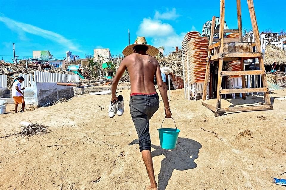 Fernando Ruiz Hernández, empleado de un restaurante en Caleta, retira escombros de la playa.