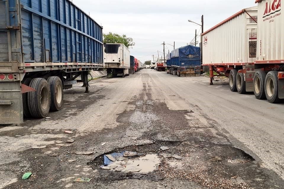 Además de que está plagada de baches, la Avenida C, contigua al arroyo, está flanqueada por unidades de carga vacías, que permanecen en el sitio por semanas.