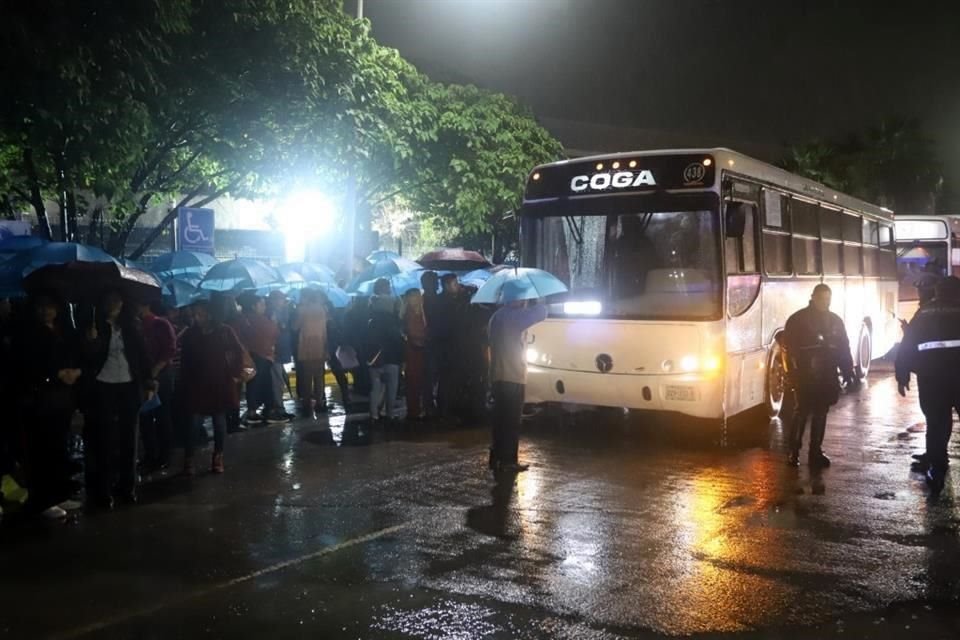 Los asistentes al evento esperaron bajo la lluvia para poder subir a los autobuses que los llevaron.