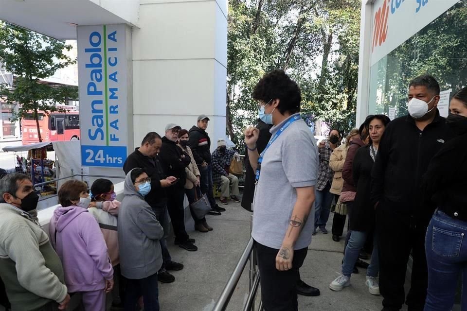 Dan instrucciones a quienes esperan afuera de farmacia.