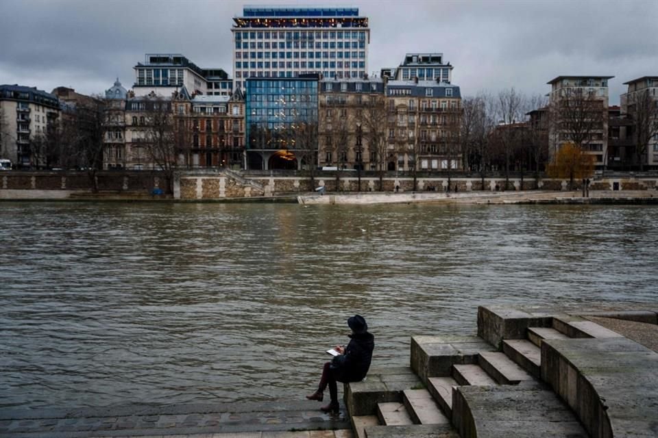 Un hombre dibuja a un lado del río Sena en París, el 26 de diciembre del 2023.