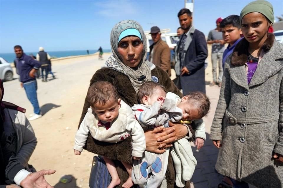 Una mujer carga a tres bebés cuando llega a la parte central de la Franja de Gaza después de huir del complejo hospitalario de Al-Shifa.