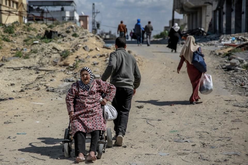 Un hombre jala a una mujer en silla de ruedas en la Ciudad de Gaza, donde cientos de miles de palestinos han quedado desplazados por la guerra.